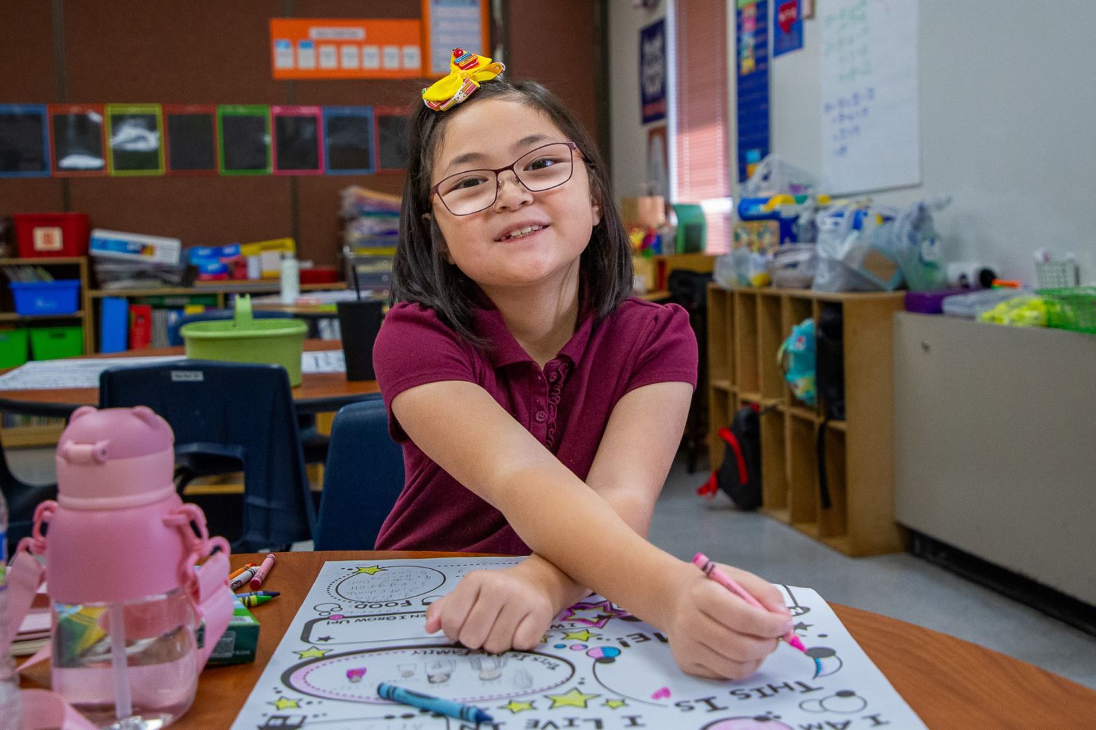 A girl smiles while coloring in her classroom at Grijalva Elementary on the first day