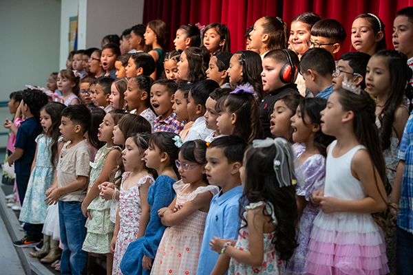 Kinder students sing on stage